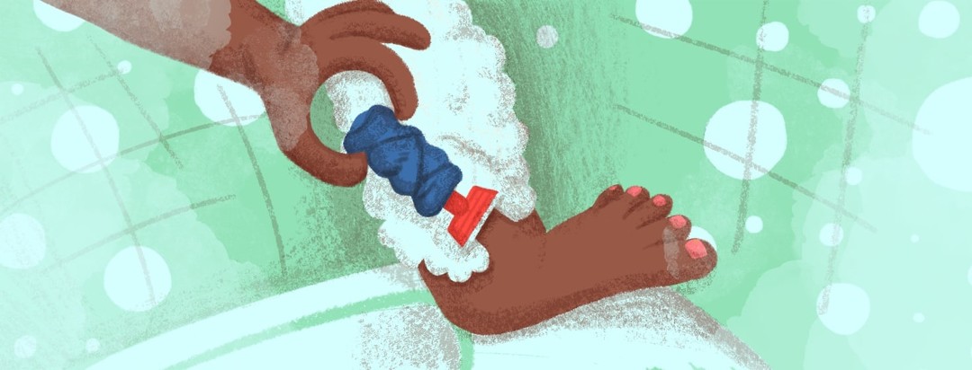 A foot resting on the edge of a bathtub with the shin and calf covered in foaming soap. A hand holding a razor which has a hand wrapped in a wash cloth comes in from the left.