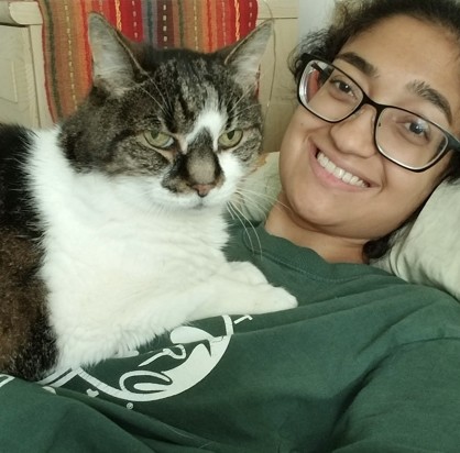 Brown and white cat and their owner in green shirt smiling at the camera.