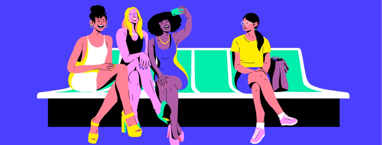 alt=woman dressed in short dresses and high heels take a selfie on the subway while another woman looks on wistfully.